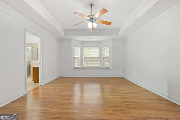 an empty room with wooden floor chandelier fan and windows