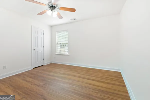 an empty room with windows and fan