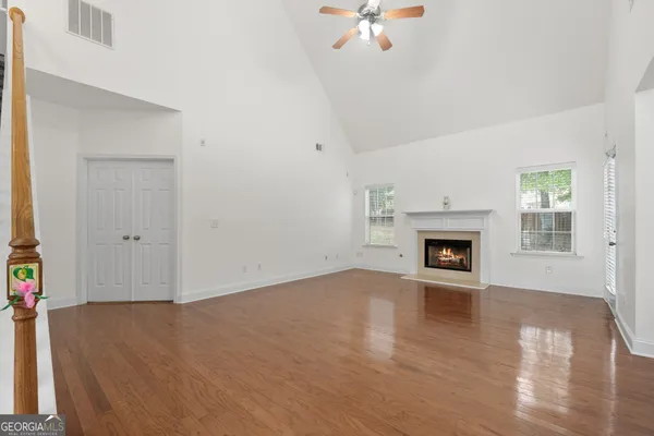 an empty room with wooden floor fireplace and windows