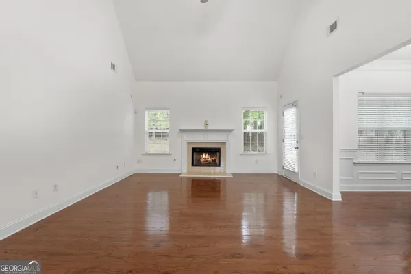 a view of an empty room with wooden floor fireplace and a window