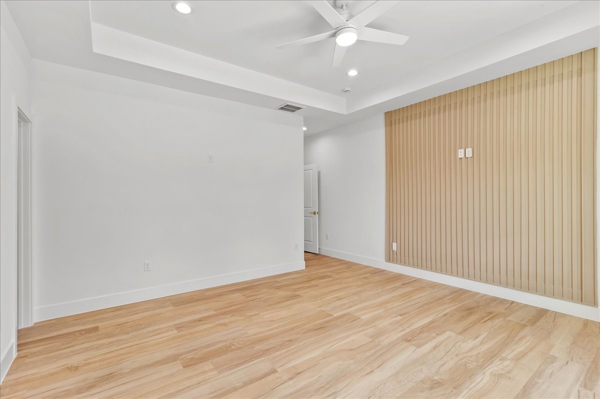 8323 Observatory Street, Unit A/B Houston, TX 77088 - Photo 8 of 38 Unit A - Spacious primary suite featuring a beautiful neutral-toned accent wall that perfectly complements the wood-look flooring, elegant coffered ceiling, and a remote-controlled ceiling fan.Accent Wall design may vary. Pictures are from a previous build.