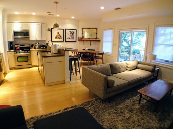 a living room with stainless steel appliances kitchen island granite countertop a couch and a view of living room