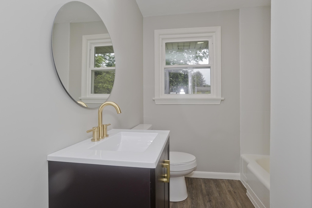 77 Drexel Street Springfield, MA 01104 - Photo 20 of 40 a bathroom with a toilet a sink a mirror and vanity