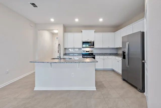 a kitchen with kitchen island a white cabinets and refrigerator