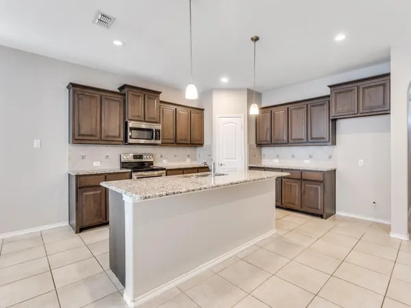 a kitchen with stainless steel appliances granite countertop a stove top oven a refrigerator a sink and a microwave