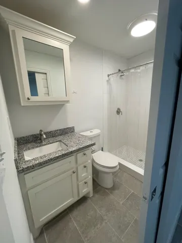 a bathroom with a granite countertop toilet a sink and a mirror