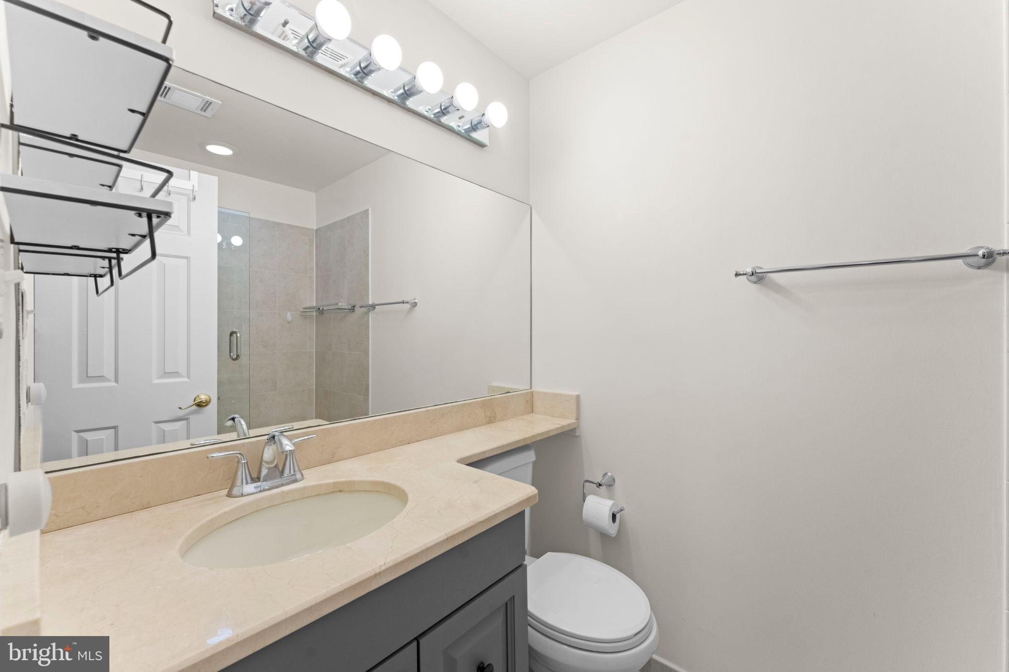 2105 North Rolfe Street, Unit A Arlington, VA 22209 - Photo 30 of 56 a bathroom with a granite countertop sink a toilet and a mirror
