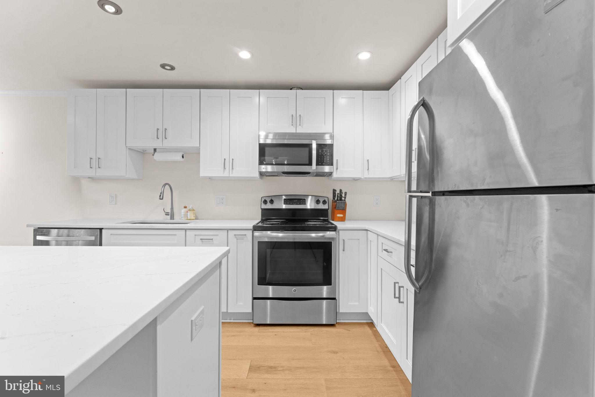 2105 North Rolfe Street, Unit A Arlington, VA 22209 - Photo 8 of 56 a kitchen with a sink a refrigerator and a stove top oven with white cabinets