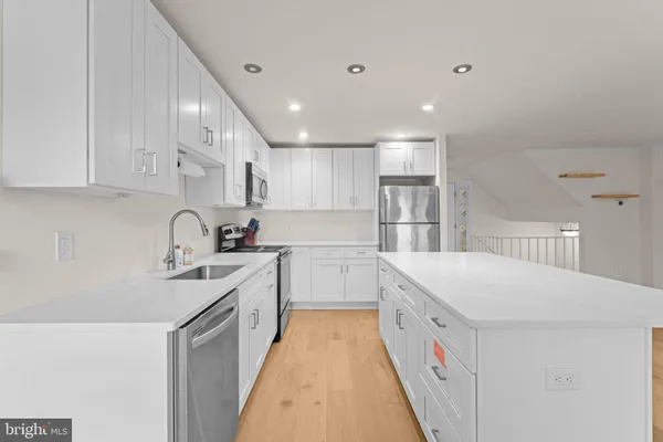 a large white kitchen with a stove a sink a refrigerator and a fireplace