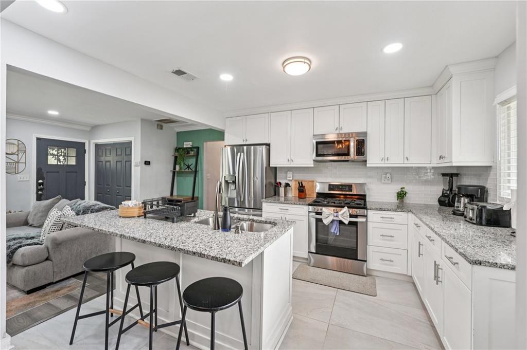 2659 Glenvalley Drive Decatur, GA 30032 - Photo 14 of 59 a kitchen with granite countertop stainless steel appliances a stove a sink a microwave a refrigerator and cabinets