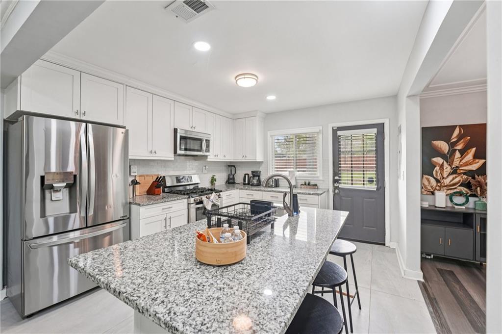 2659 Glenvalley Drive Decatur, GA 30032 - Photo 17 of 59 a kitchen with stainless steel appliances granite countertop a refrigerator a stove a sink dishwasher a dining table and chairs with wooden floor