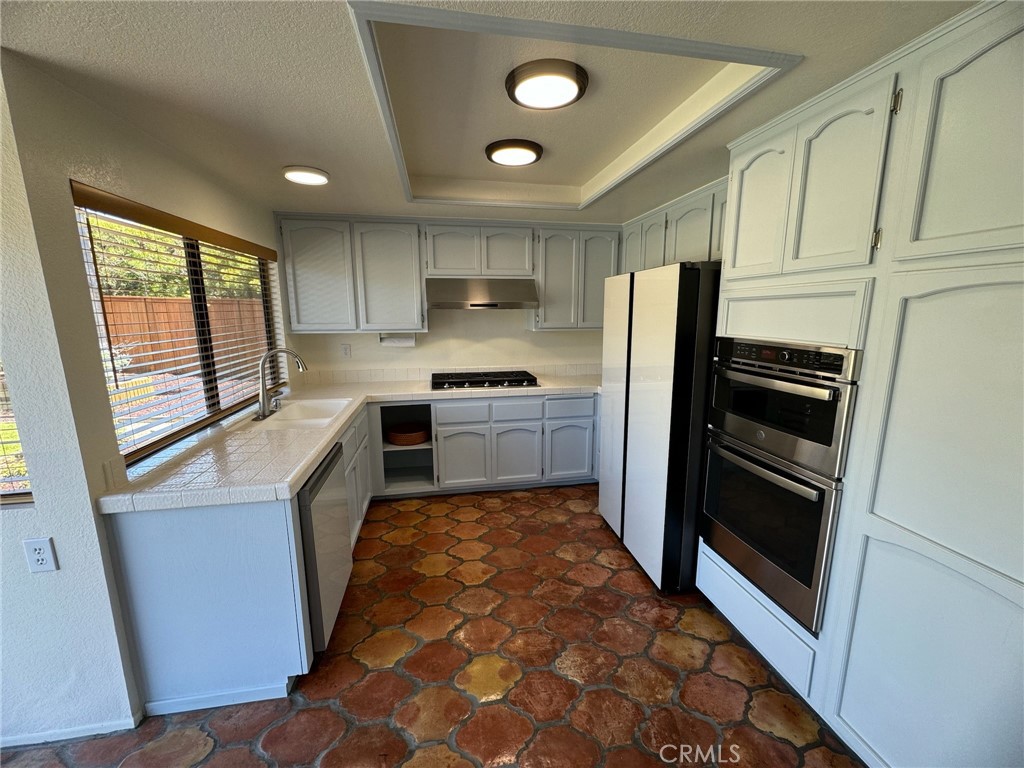 27515 Via Valor Dana Point, CA 92624 - Photo 7 of 24 a kitchen with stainless steel appliances granite countertop a refrigerator oven a sink dishwasher and white cabinets with wooden floor