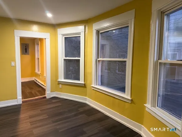 a view of an empty room with wooden floor and windows
