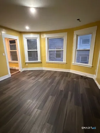 a view of an empty room with wooden floor and windows