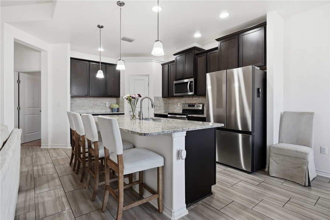 1026 Pasadena Street Portland, TX 78374 - Photo 13 of 30 a kitchen with stainless steel appliances granite countertop a refrigerator a microwave a sink and a refrigerator
