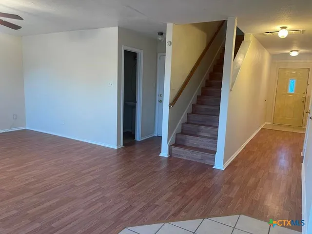 a view of a hallway with wooden floor and stairs