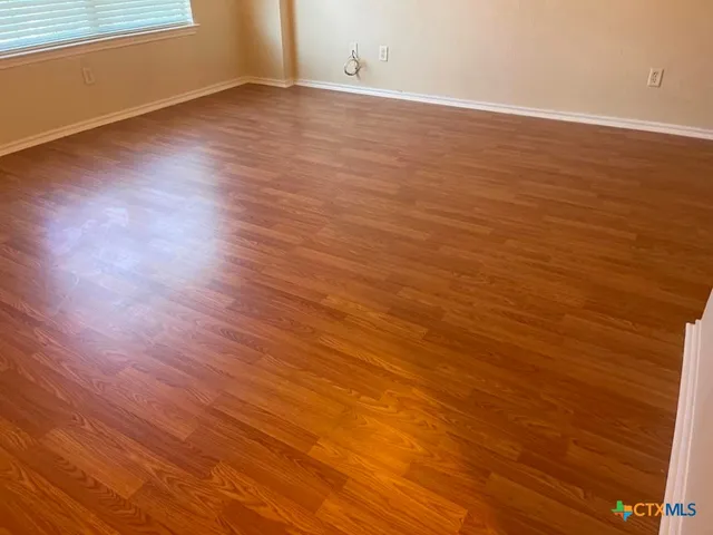 a view of an empty room with wooden floor