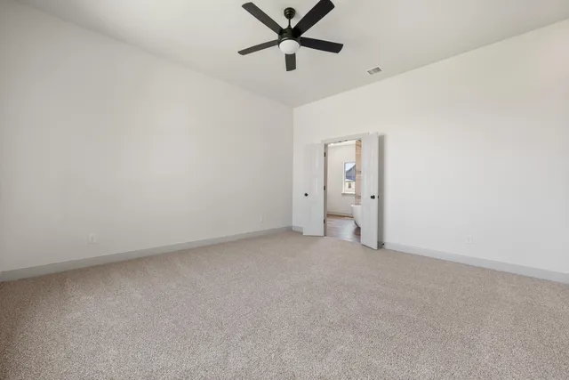 an empty room with closet and a ceiling fan
