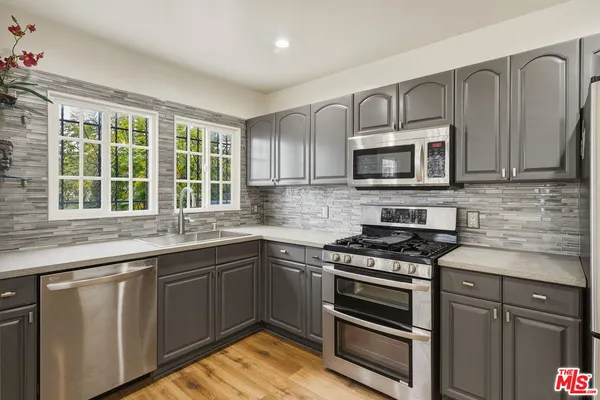 a kitchen with granite countertop stainless steel appliances a refrigerator cabinets and a window