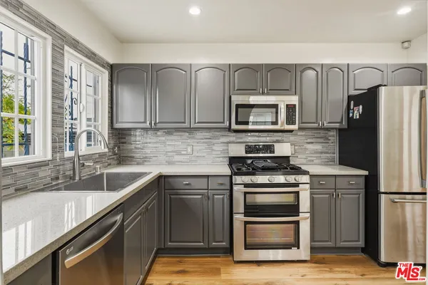 a kitchen with stainless steel appliances granite countertop a stove a sink and a refrigerator