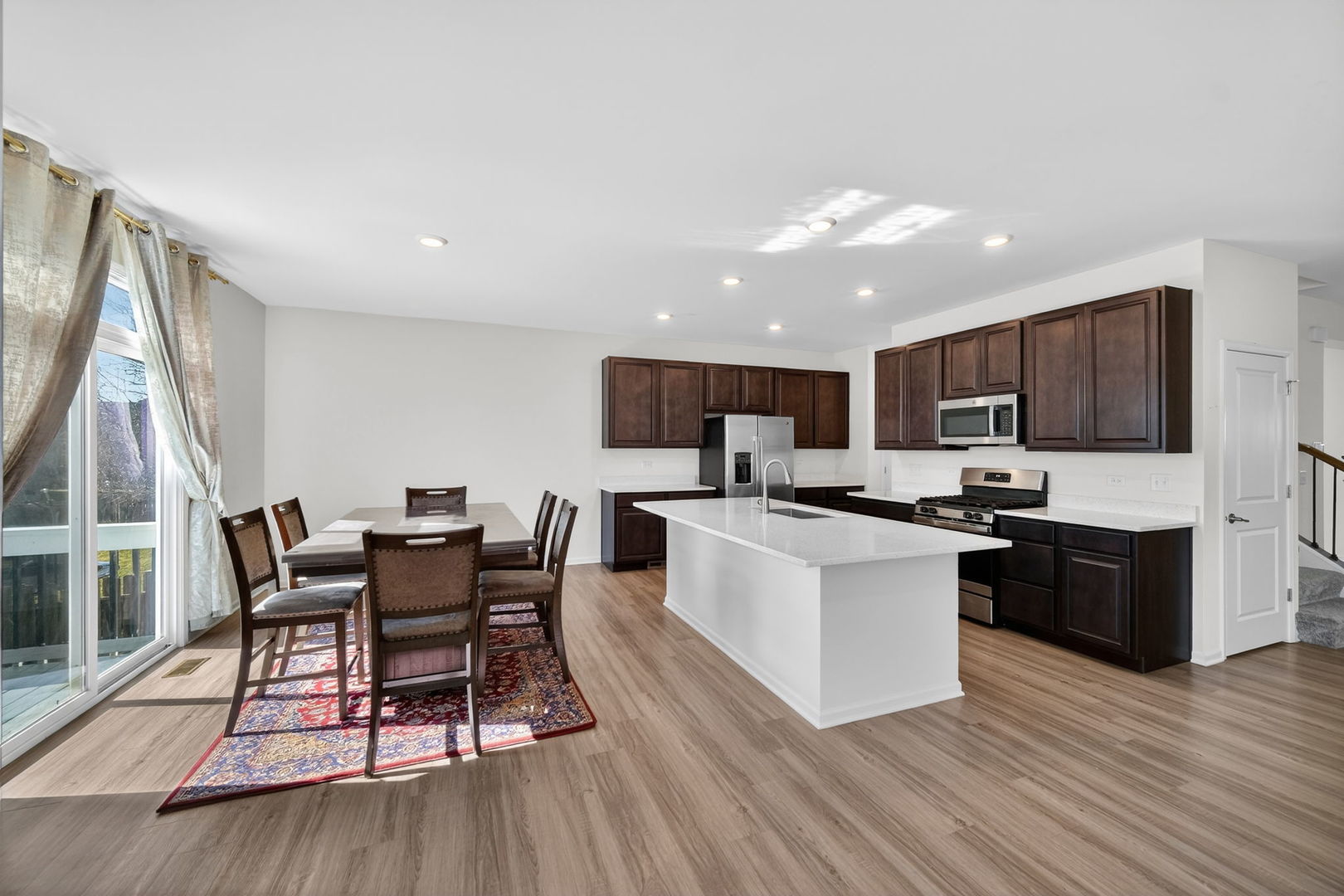 3803 Ivy Lane Elgin, IL 60124 - Photo 13 of 43 a kitchen with stainless steel appliances kitchen island granite countertop a stove top oven a sink dishwasher a dining table and chairs with wooden floor