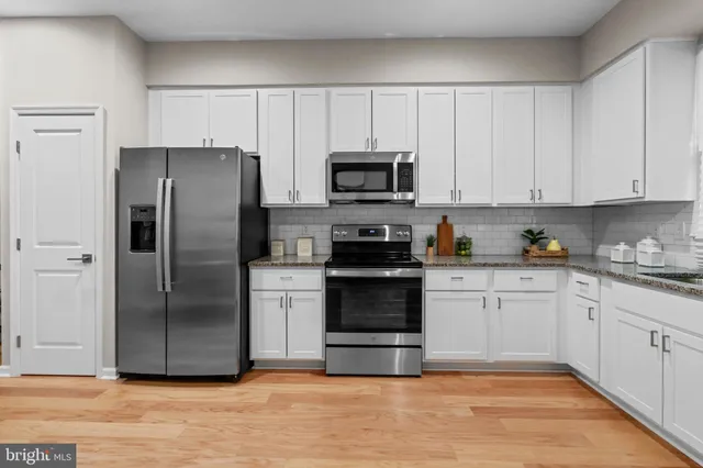 a kitchen with a refrigerator stove and white cabinets