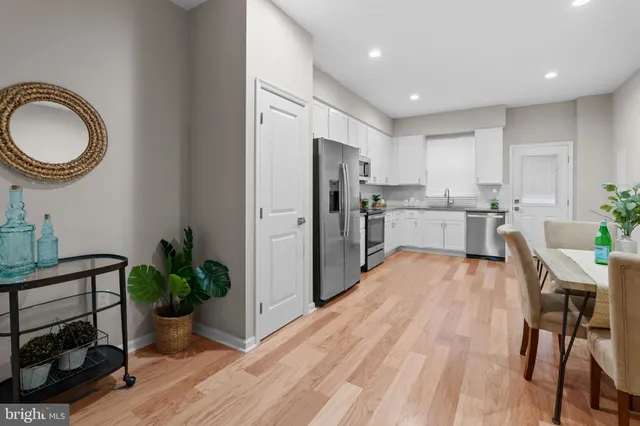 a kitchen with stainless steel appliances a dining table chairs stove and refrigerator