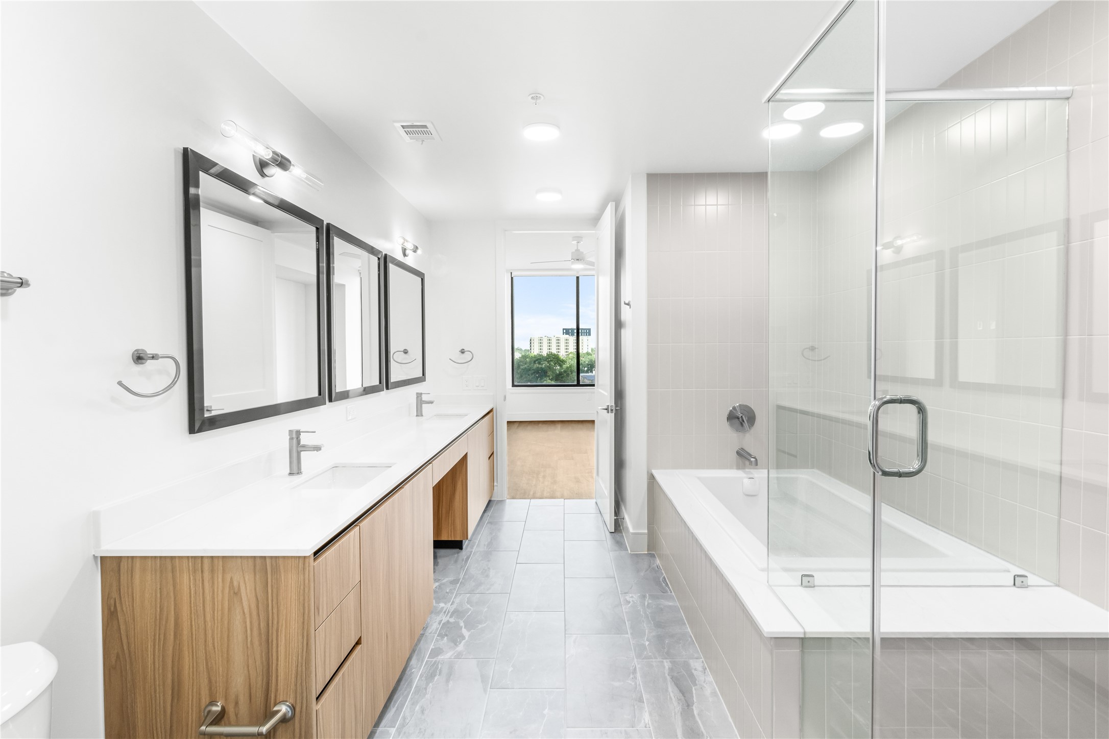 2311 Westheimer Road, Unit 914 Houston, TX 77098 - Photo 13 of 29 a bathroom with a double vanity sink a mirror and a bathtub