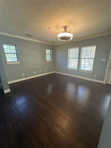 an empty room with wooden floor chandelier and window