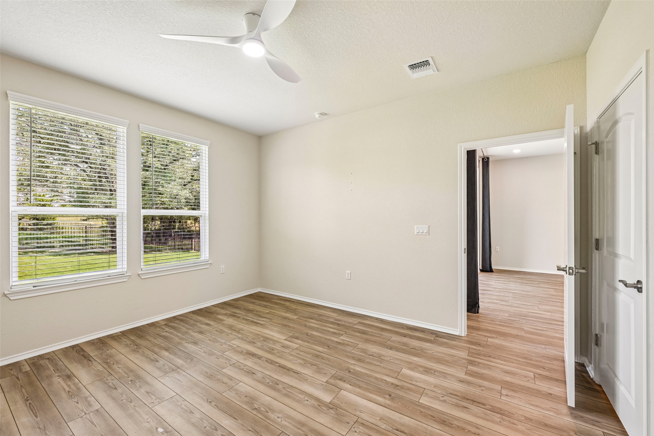 401 Yorktown Street Georgetown, TX 78633 - Photo 21 of 38 Room featuring wood-finish flooring, two large windows with blinds, a modern ceiling fan, and painted walls