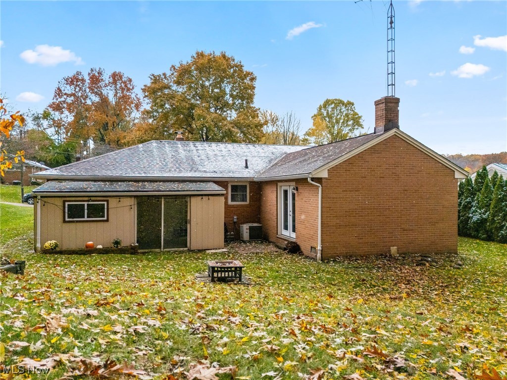 4727 15th Street Northwest Canton, OH 44708 - Photo 35 of 37 Back of property featuring a fire pit, a yard, brick siding, and a chimney