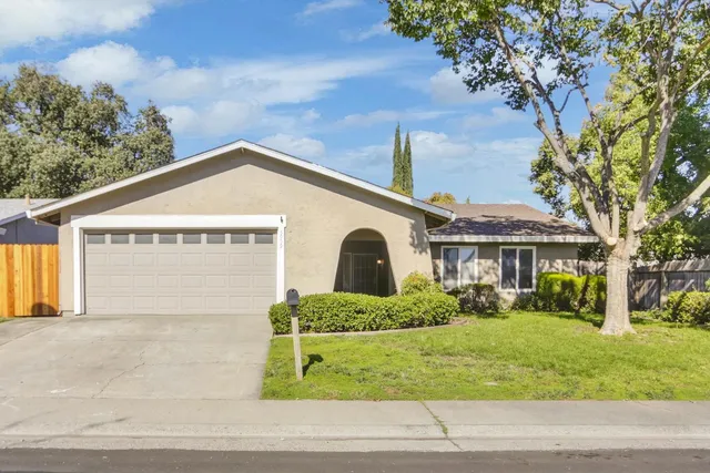 a front view of a house with garage and plants
