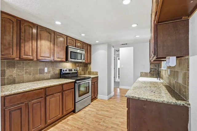 a kitchen with stainless steel appliances granite countertop a stove a sink and a refrigerator