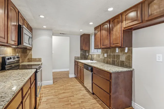 a kitchen with granite countertop wood cabinets stainless steel appliances and a counter space