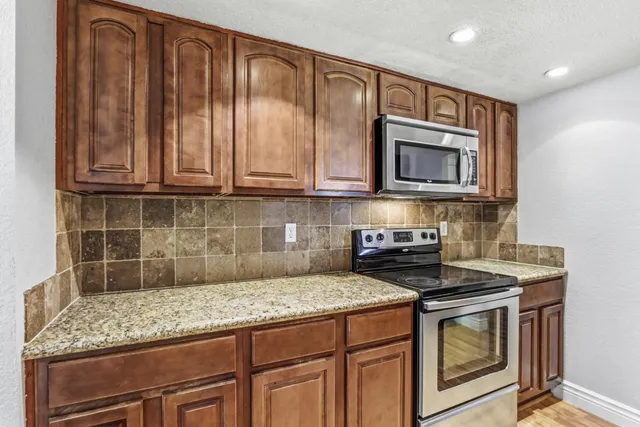 a kitchen with stainless steel appliances granite countertop wooden cabinets stove top oven and sink