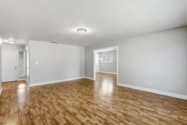 a view of an empty room with window and wooden floor