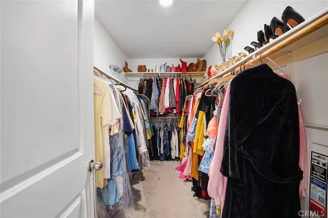 a view of walk in closet with clothes and shoes