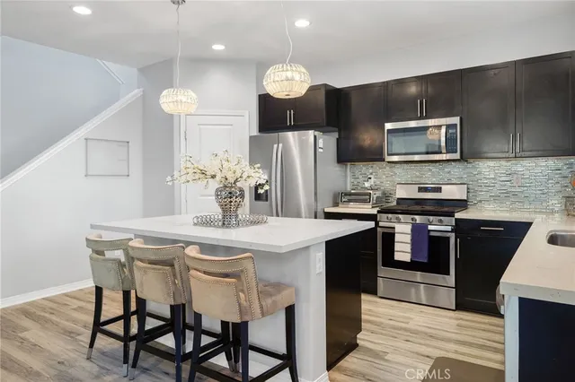 a kitchen with stainless steel appliances granite countertop a stove top oven a refrigerator a sink and a microwave