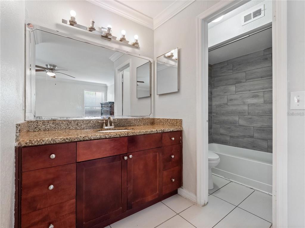 5144 Conroy Road, Unit 27 Orlando, FL 32811 - Photo 10 of 20 a bathroom with a granite countertop sink a mirror and a bathtub