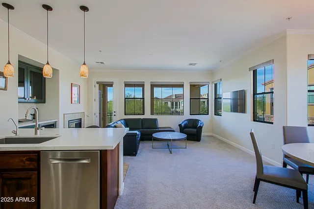 a living room with stainless steel appliances furniture a rug and a view of kitchen