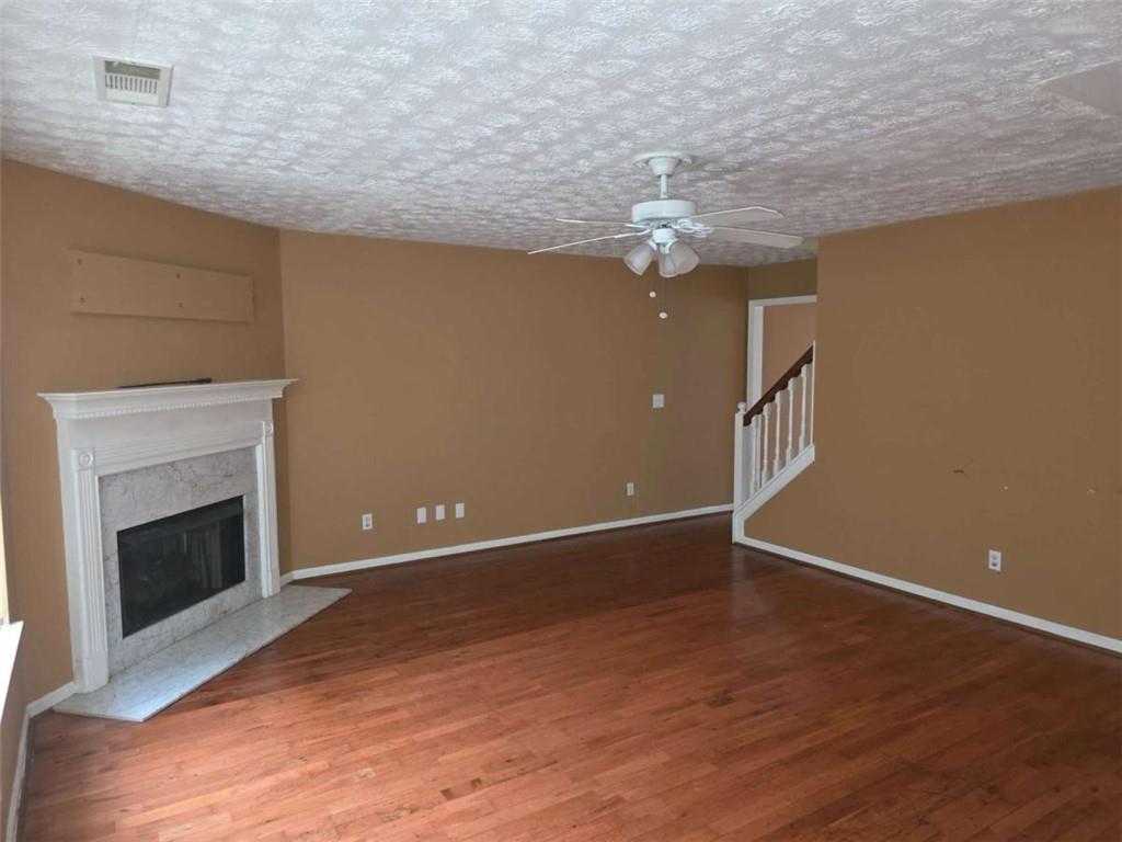4410 Cross Lane Decatur, GA 30035 - Photo 5 of 26 an empty room with wooden floor a chandelier fan and a fireplace
