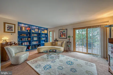 a living room with furniture a bookshelf and a window