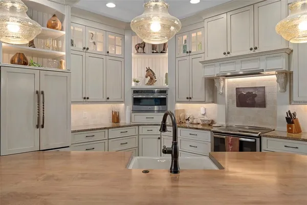 a kitchen with stainless steel appliances granite countertop a dining table chairs and wooden floor