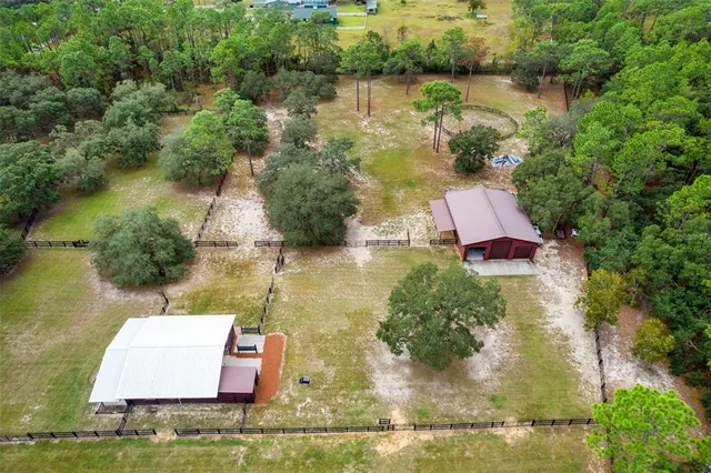 an aerial view of residential houses with outdoor space and trees