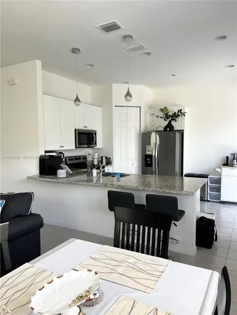 a kitchen with a sink dishwasher a dining table and chairs with wooden floor