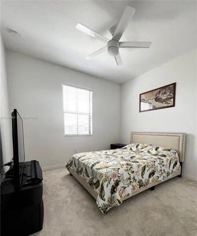 a bedroom with a bed next to a window with a flat screen tv