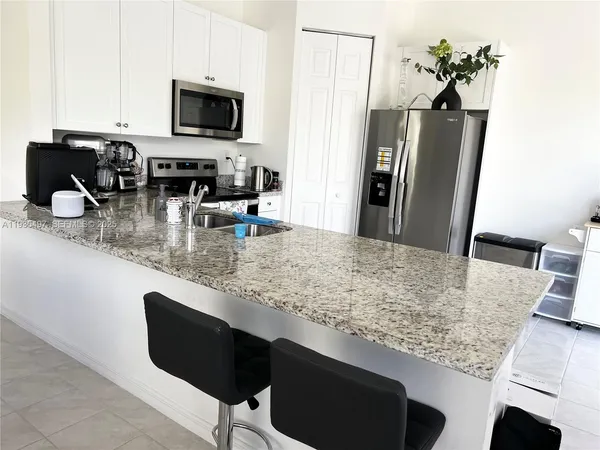 a kitchen with stainless steel appliances granite countertop a refrigerator a stove a microwave a sink and white cabinets