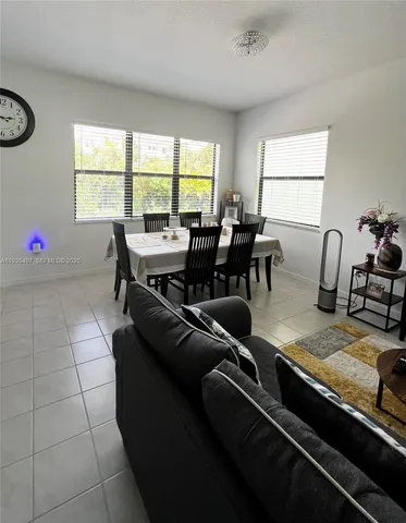 a living room with furniture two window and a dining table