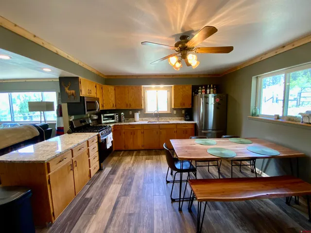 a kitchen with stainless steel appliances kitchen island granite countertop a table chairs sink and cabinets