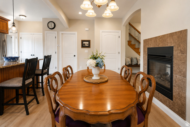 896 Cres Drive South Mapleton, UT 84664 - Photo 7 of 32 Dining area featuring a tile-surround fireplace, wood-finish flooring, and a chandelier